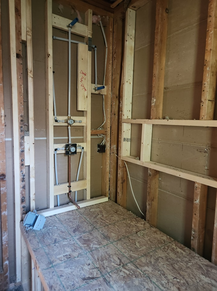 A bathroom under construction with wooden walls and a wooden floor.