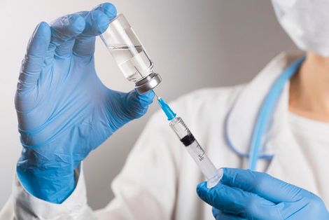 Medico che tiene in mano il test per il COVID-19 e scrive sulla cartella clinica del paziente. Guanti e blocco per appunti visibili.