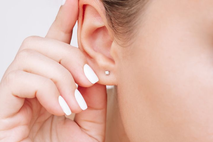 Un medico con guanti blu aspira un liquido da una fiala con una siringa.