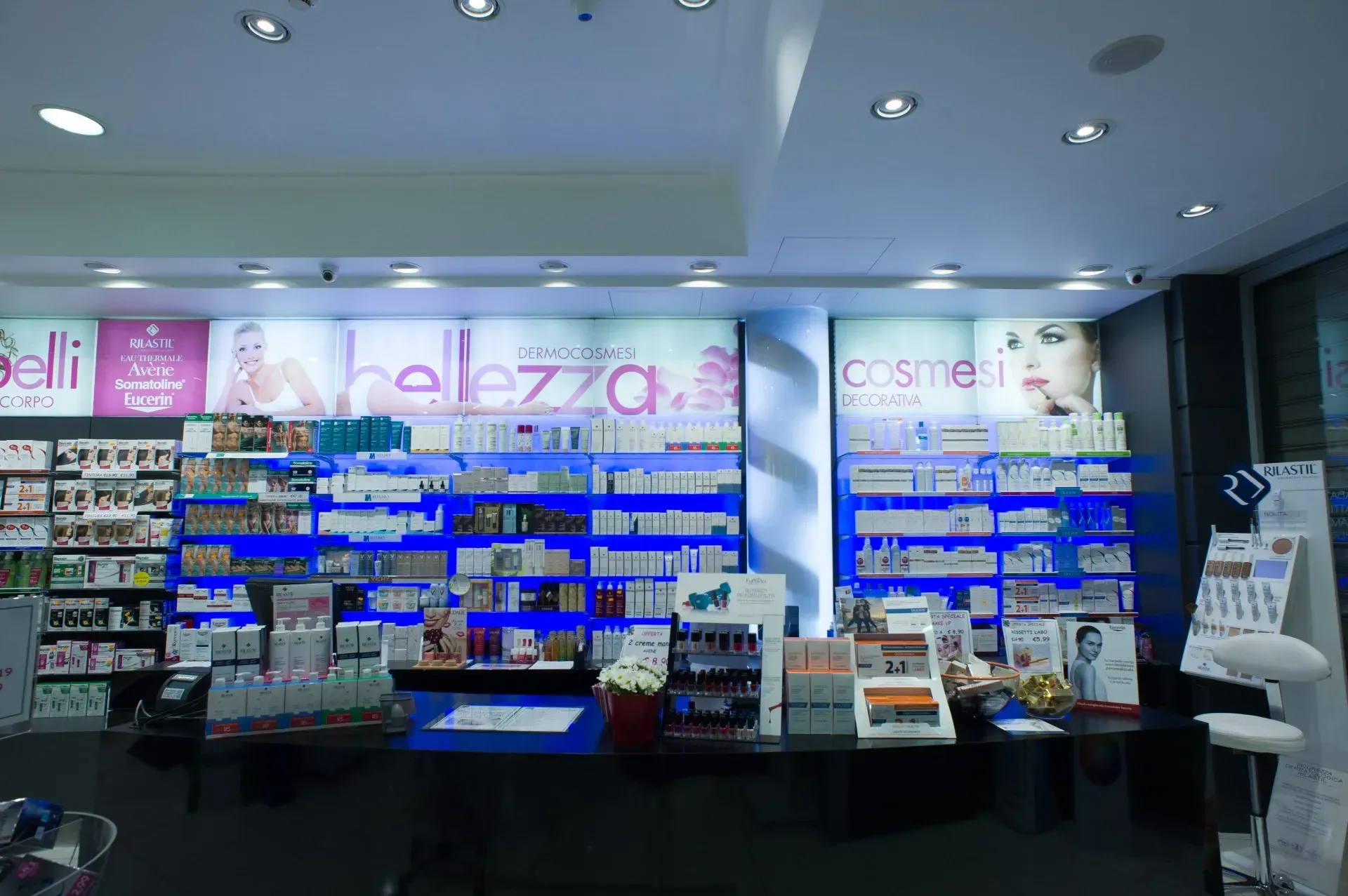 Interno di una farmacia con scaffali illuminati pieni di prodotti di bellezza.