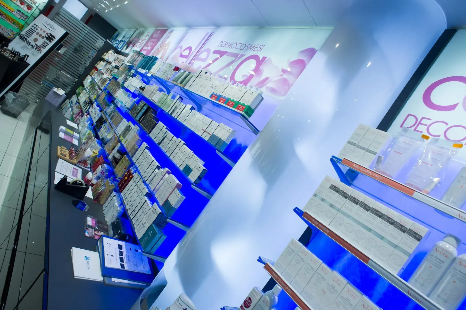 Scaffali di prodotti di bellezza in un negozio, illuminazione blu, vista angolata.