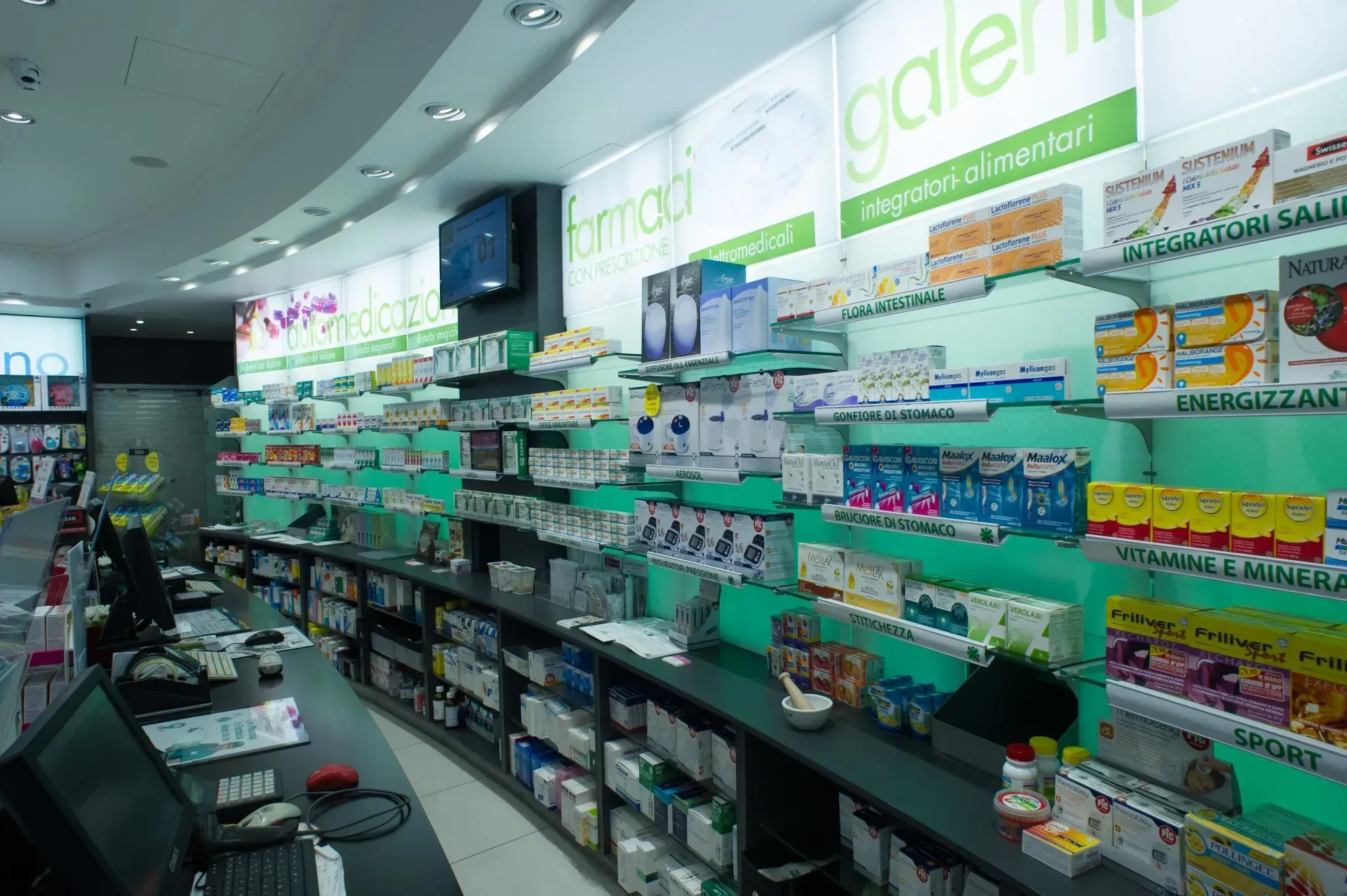 Interno di una farmacia con scaffali di medicinali e un bancone.