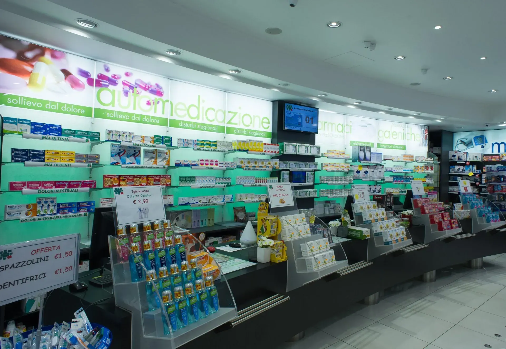 Interno di una farmacia con scaffali di medicinali dietro un bancone e prodotti esposti.