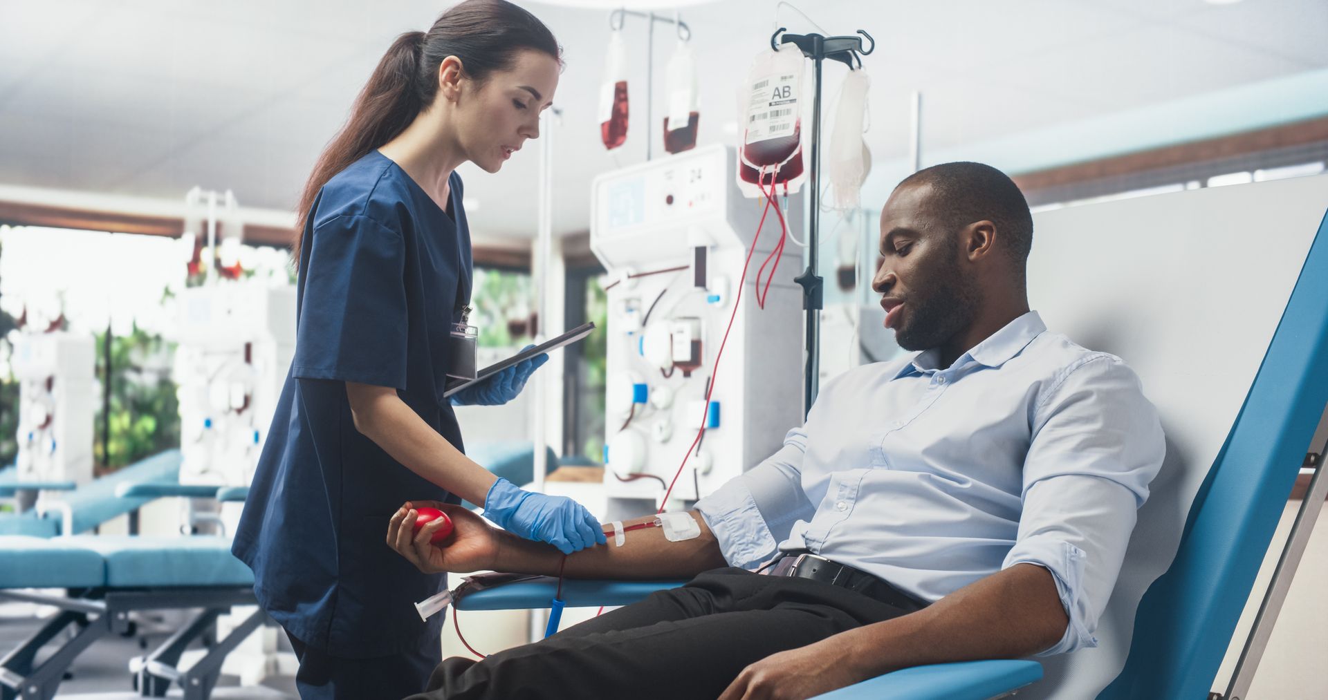 A healthcare professional monitors a person donating blood in a medical facility.