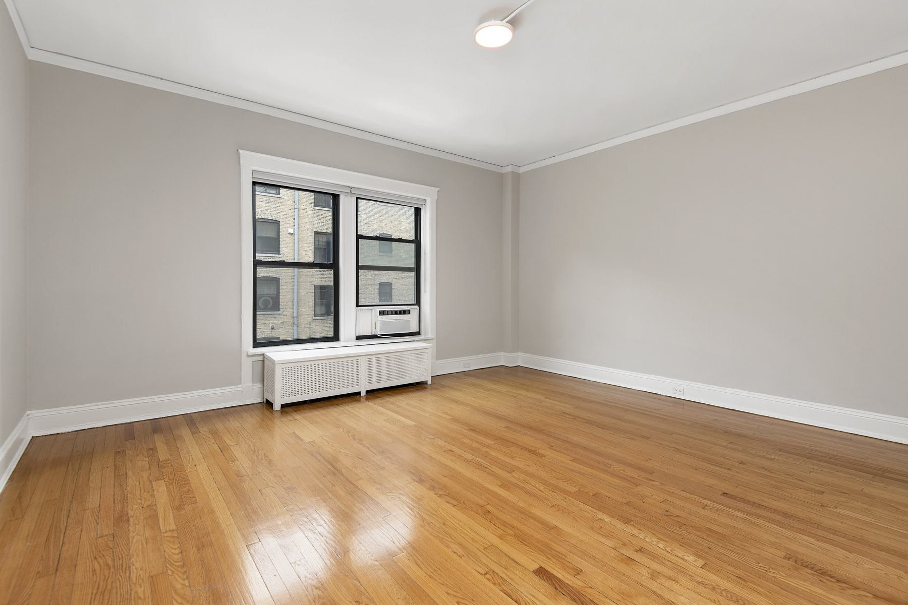 an empty living room with wood floors and a window