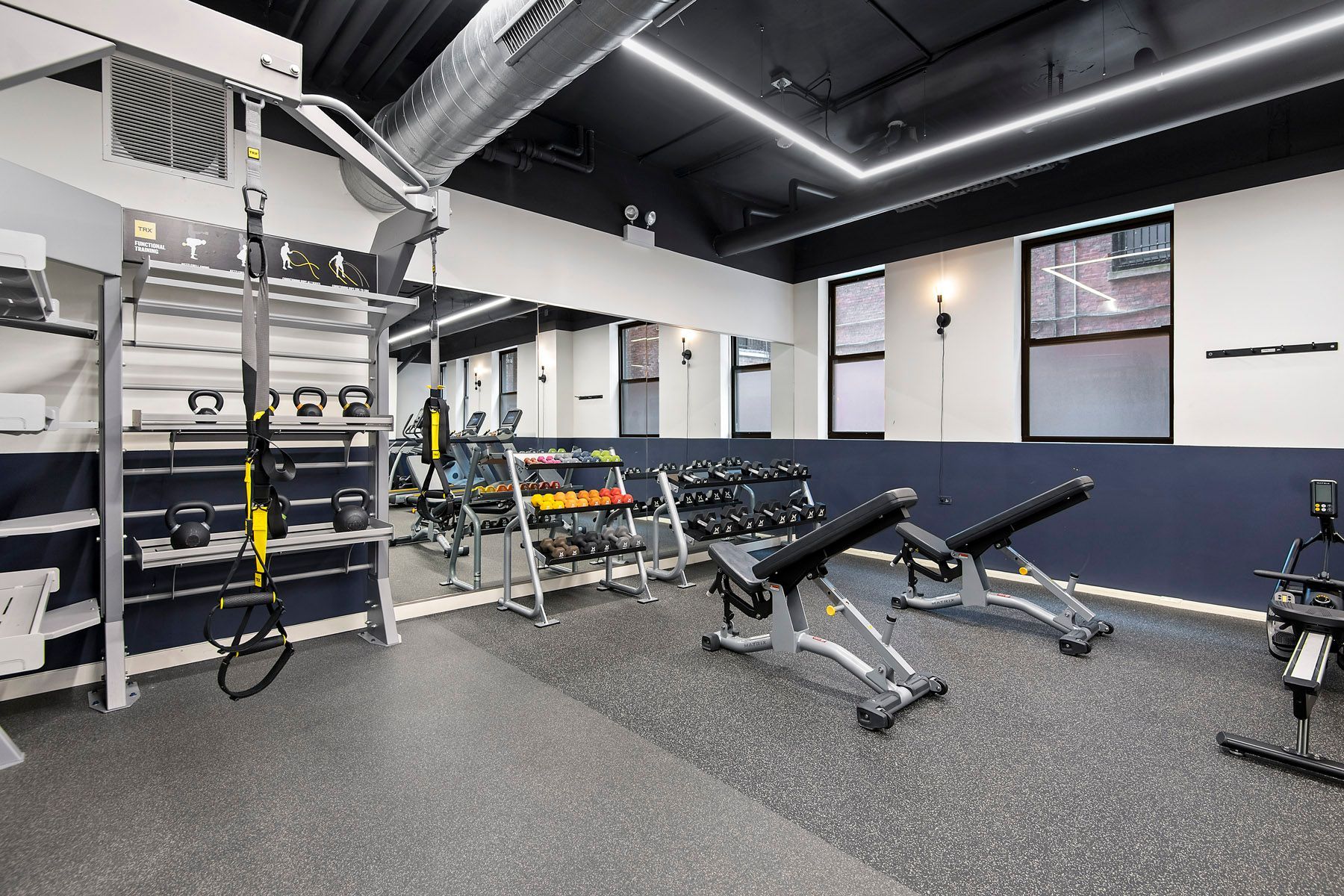 A gym with a lot of exercise equipment and a large mirror at Park Fullerton by Reside. 