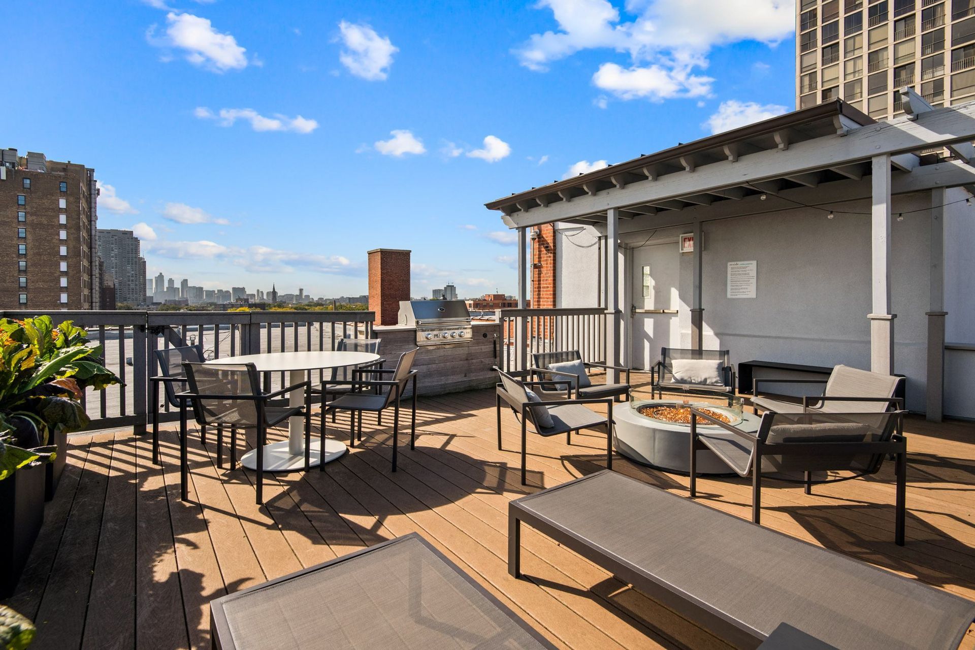 a rooftop patio with tables and chairs and a fire pit