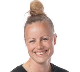 Smilende kvinde med hår i en knold, iført en sort top.