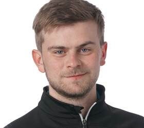 Mand med kort, lysebrunt hår og et let smil, iført en sort lynlåsjakke.