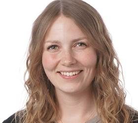 Kvinde med lysebrunt, bølget hår smiler til kameraet.