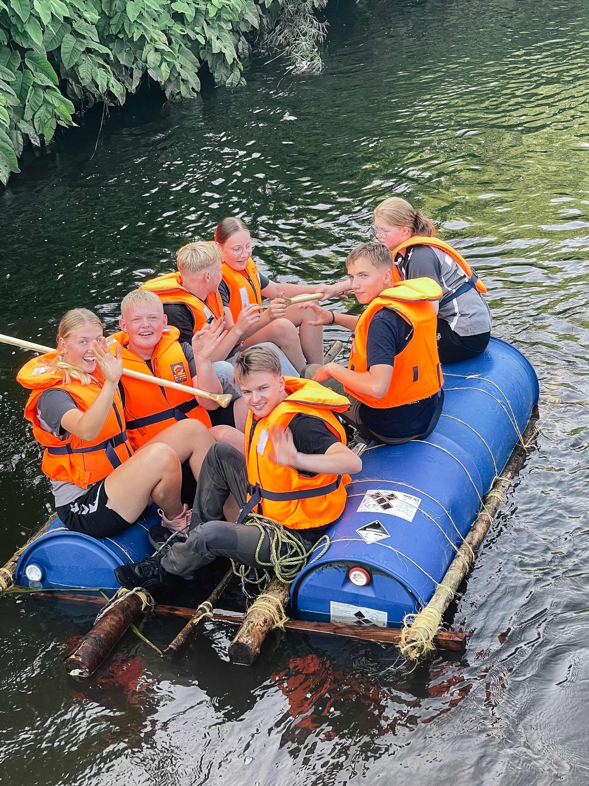 Rød murstensbygning med glasindgang, rødt tegltag og gårdsplads.