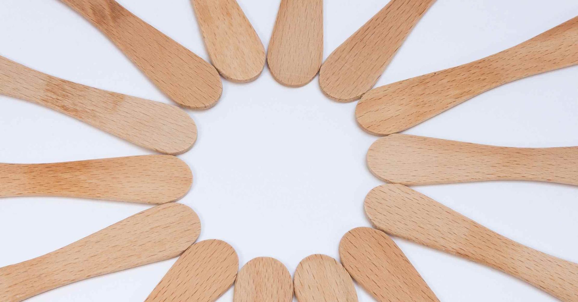 Træpinde arrangeret i en cirkel på en hvid baggrund, hvilket skaber et tomt centrum.
