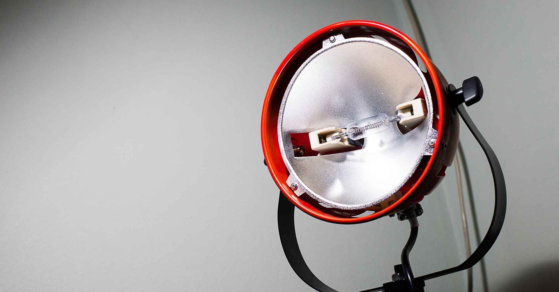 Orange og sølvfarvet spotlight, vinklet mod en væg.