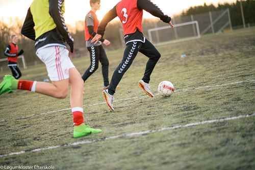 Fodboldspillere træner på en bane, en sparker bolden.