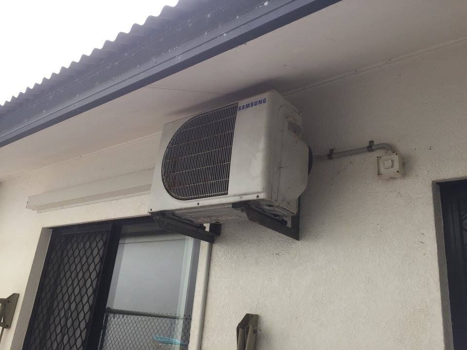 Air Conditioner Unit Mounted on a White Building Exterior Near a Window — Active Airconz in Perth, WA