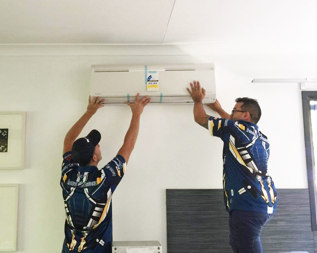 Repair Men In Active Airconz Shirt Fitting New Air Conditioner — Active Airconz in Winnellie, NT