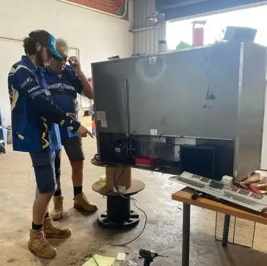 Two Men Are Working On A Refrigerator In A Garage — Active Airconz in Darwin, NT