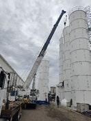 Una grúa levanta un silo de hormigón en una fábrica.