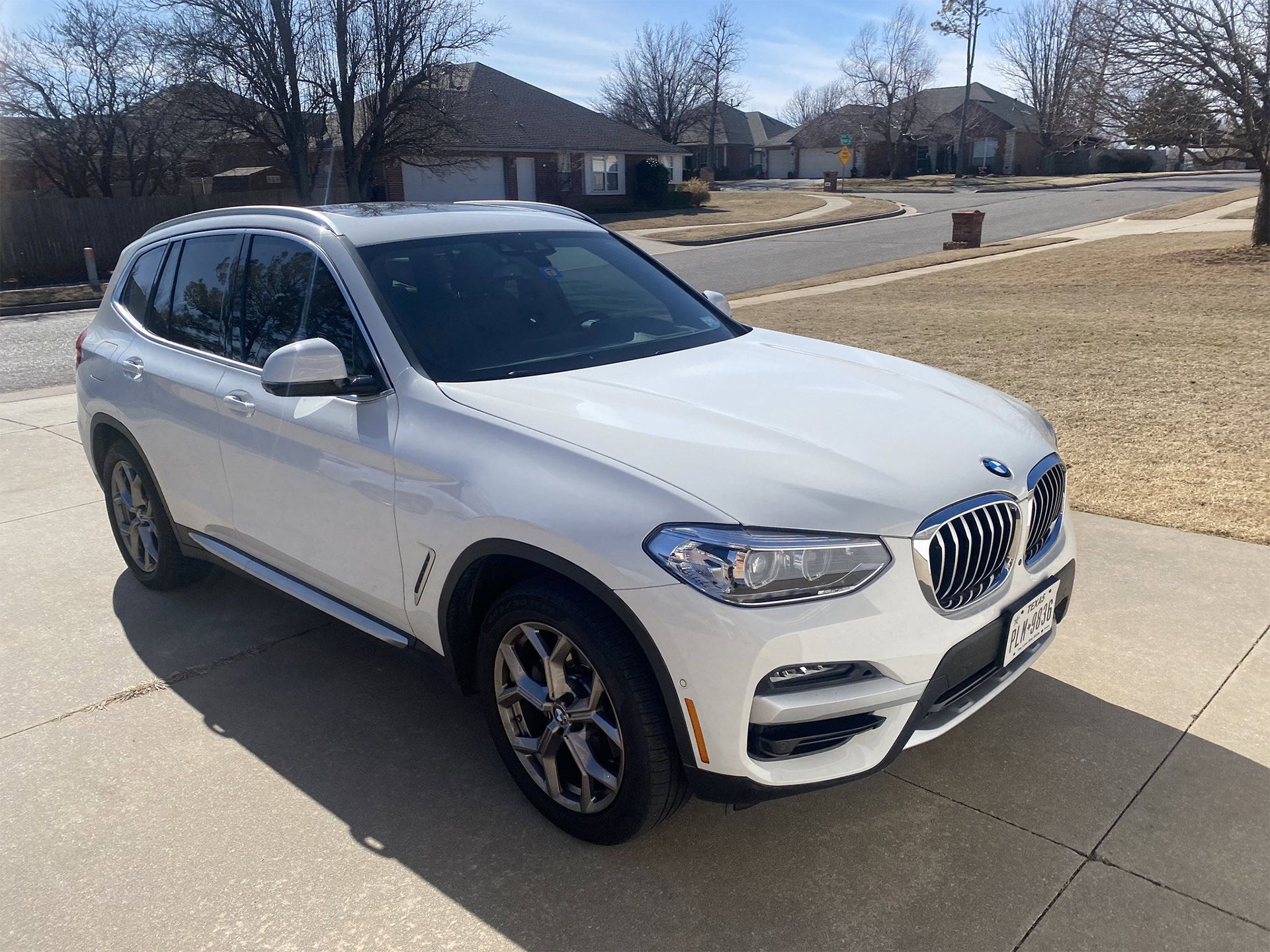 A white bmw x3 is parked on the side of the road being detailed