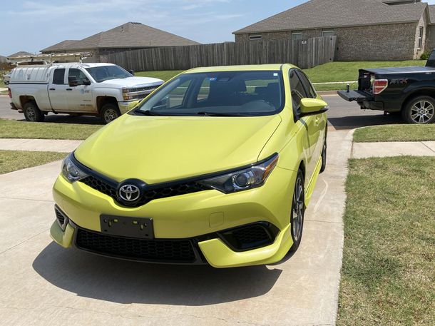 A yellow car is parked in a driveway being detailed