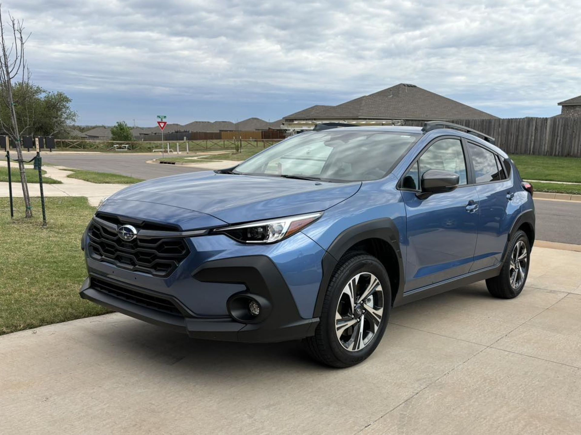 A blue subaru xv is parked in a driveway in front of a house being washed