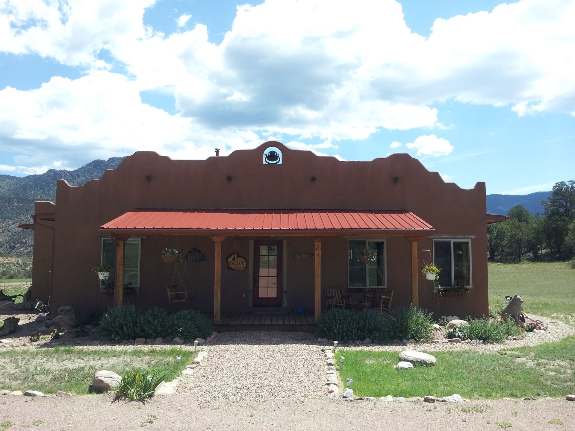 A house with a red roof and mountains in the background