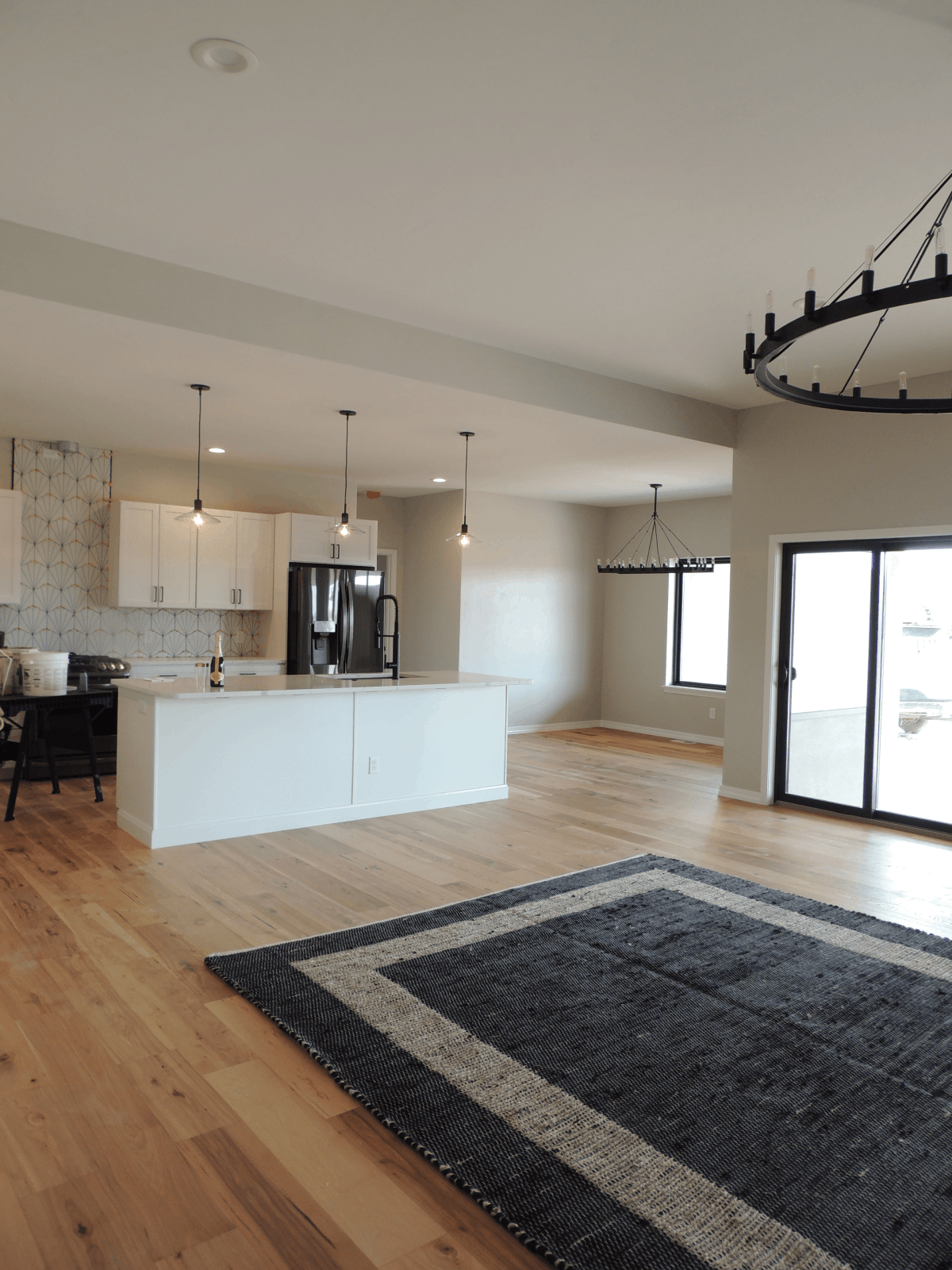 A living room with hardwood floors , a rug , and a kitchen.