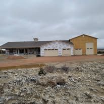 A large house is sitting in the middle of a dirt field.