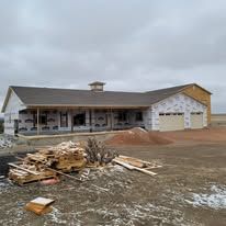 A large house is being built in the middle of a dirt field.