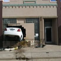 A car is stuck in the side of a building.