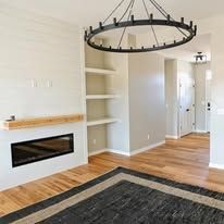 A living room with hardwood floors , a fireplace , a rug and a chandelier.