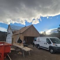 A white van is parked in front of a house under construction.