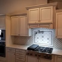 A kitchen with white cabinets , a stove top oven , and a microwave.