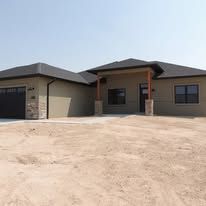 A large house is sitting on top of a dirt field.