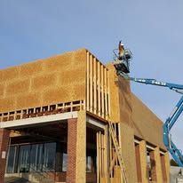 A man is working on the side of a building with a crane.
