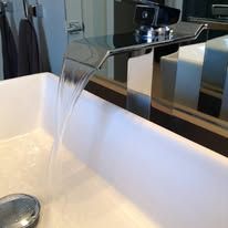A waterfall faucet is pouring water into a bathroom sink.