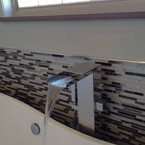 A waterfall faucet is coming out of a bathtub in a bathroom.
