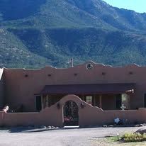 A large adobe house with mountains in the background.