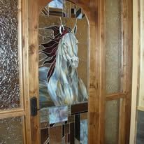 A stained glass door with a horse on it.