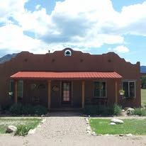 A brown house with a red roof and a porch on a sunny day.