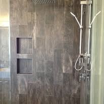 A shower with a stainless steel shower head and a glass door.