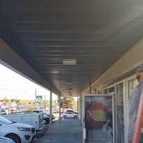 A man is standing under a covered walkway in front of a building.