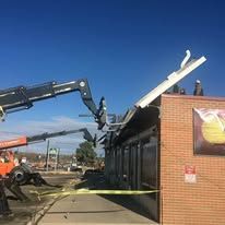 A crane is lifting the roof of a building.