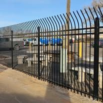 A black wrought iron fence surrounds a parking lot.