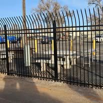 A metal fence with a picnic table and chairs behind it.