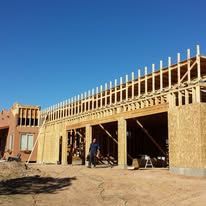 A large house is being built in the desert with a blue sky in the background.