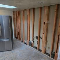 A kitchen with a stainless steel refrigerator and a wooden wall.