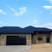 A house with a black roof and a black garage door.