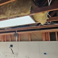 The ceiling of a building is being remodeled with wooden beams and insulation.