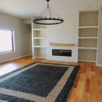 A living room with hardwood floors , a fireplace , a rug and a chandelier.